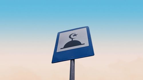 Low angle view of road sign against clear blue sky