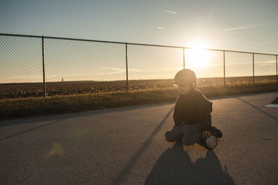Young boy riding hover board in warm sunlight near fence