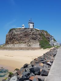 Lighthouse by building against clear blue sky