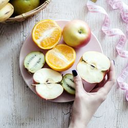 Cropped hand of woman holding apple on table