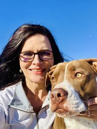 Portrait of smiling woman with dog against clear blue sky