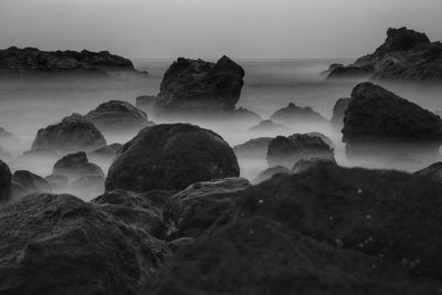 Rocks on sea shore against sky