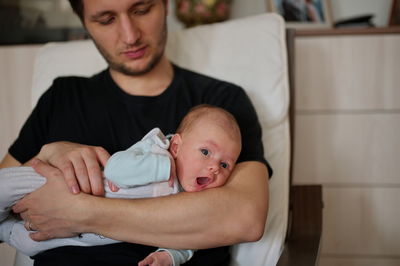 Portrait of man holding newborn baby girl