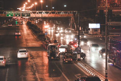 Cars on illuminated street in city at night