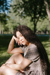 Young woman looking away while sitting on tree