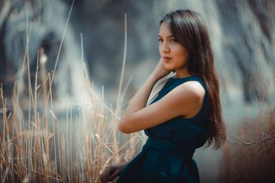 Thoughtful young woman looking away while standing by plants