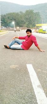 Young man lying on road in city