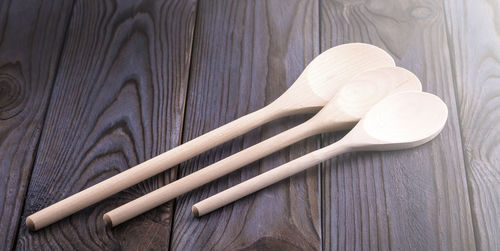 Three wooden spoons on a wooden table on soft sunlight