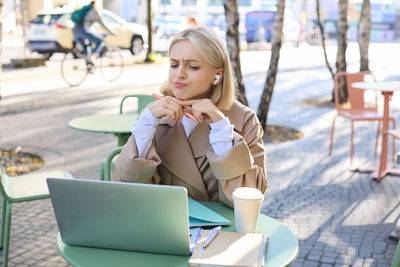 Young woman using laptop while sitting on chair