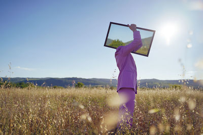 Woman standing on field against sky