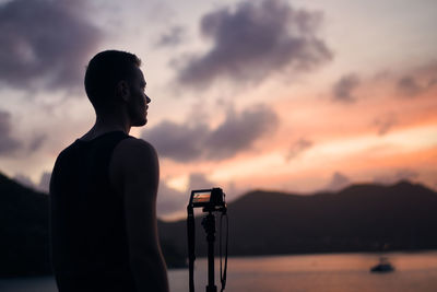 Silhouette man photographing camera against sky during sunset