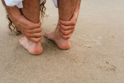 Low section of man standing on sand