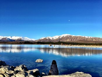 Scenic view of lake and mountains against clear blue sky