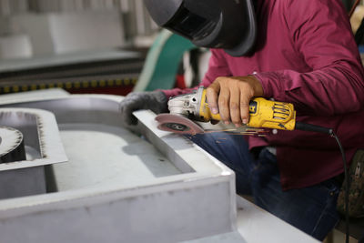 The worker is welding steel frame in work shop.