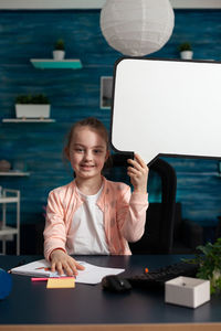 Portrait of cute girl holding poster