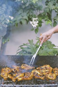 Midsection of person preparing food on barbecue grill