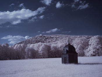 Built structure on snow covered field against sky