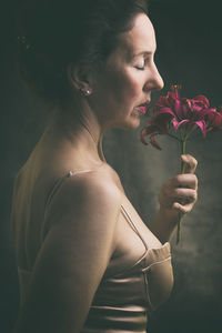 Side view of young woman holding flower