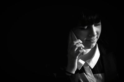 Close-up of young woman against black background