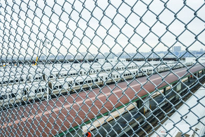 Close-up of trains seen through chainlink fence against clear sky