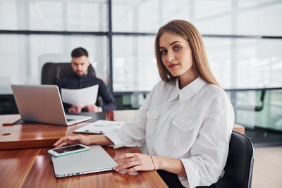 Portrait of young woman using laptop at office