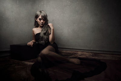 Portrait of woman sitting against wall