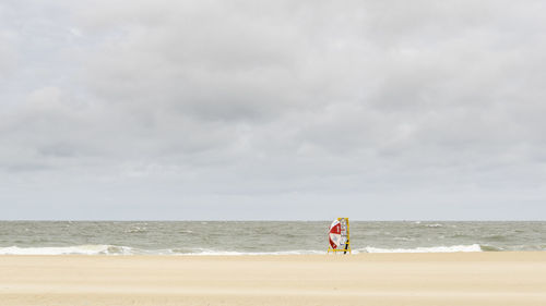 Man walking on beach against sky