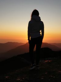 Full length of silhouette woman standing on land against sky during sunset