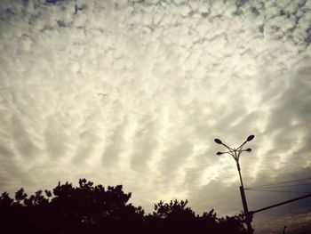 Low angle view of power lines against cloudy sky