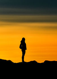 Silhouette woman standing on mountain against sky during sunset