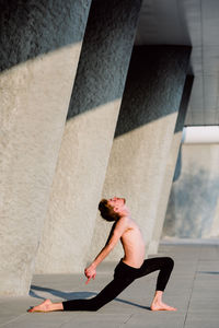 Shirtless young man exercising by columns