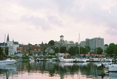 Sailboats moored in harbor against buildings in city