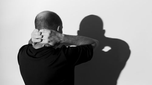 Midsection of man with arms raised against white background