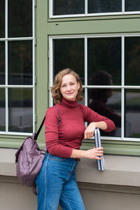 Young caucasian girl going back to college, school, standing with a notebooks