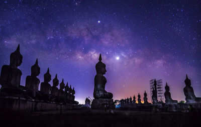 Low angle view of statue against buildings at night