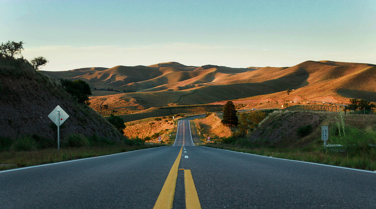 EMPTY ROAD ALONG MOUNTAIN RANGE AGAINST SKY