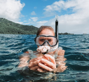 Portrait of woman holding coral in sea