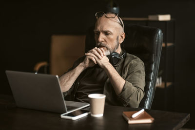 Young man using mobile phone while sitting on table