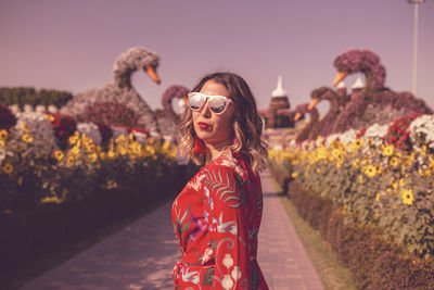 Woman wearing sunglasses while standing on footpath