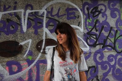 Young woman standing against graffiti wall