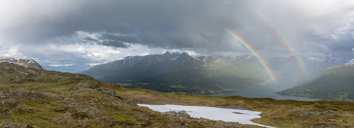 Scenic view of double rainbow over hamperokken mountains against cloudy sky