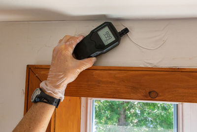 Midsection of man holding mobile phone at home