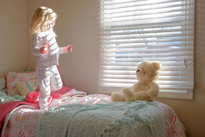 Girl with dog toy on bed at home