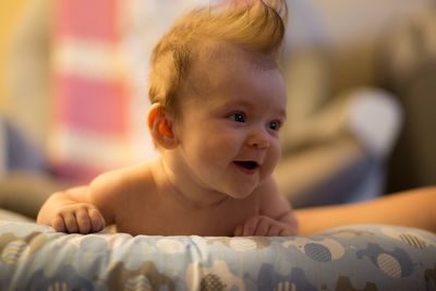 Close-up of cute shirtless baby lying on bed at home