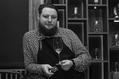 Portrait of man holding wineglass while standing in restaurant