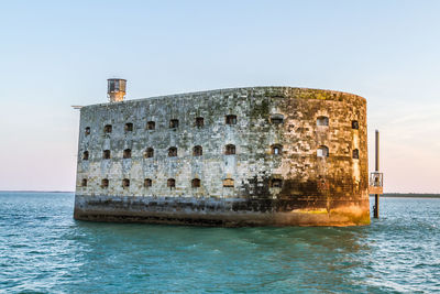 Built structure by sea against clear sky