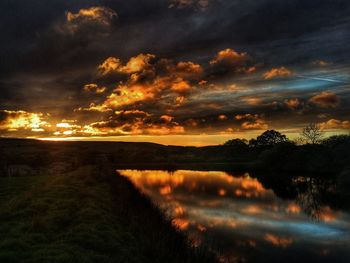 Scenic view of dramatic sky over lake during sunset