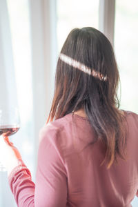 Rear view of woman drinking glass window