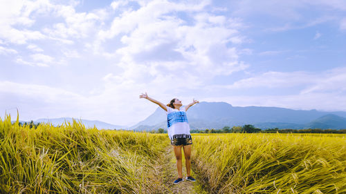 Rear view of woman standing on field against sky