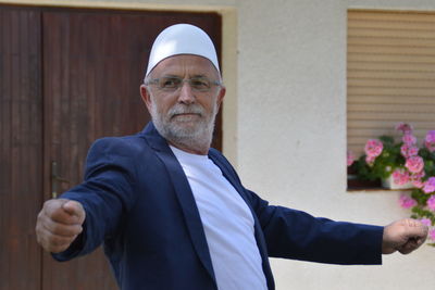 Senior man wearing blazer by door looking away